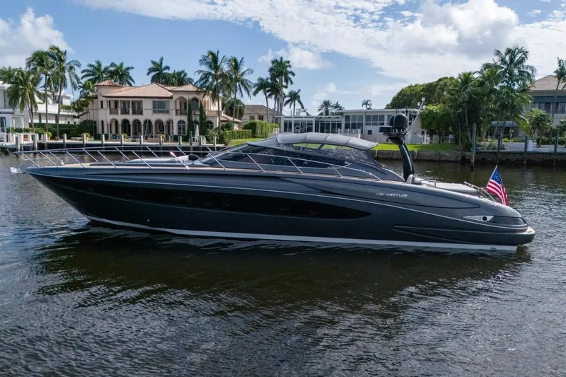 The Image of 2015 Riva 63 yacht cruising on a scenic waterway with luxury homes and palm trees. - 0
