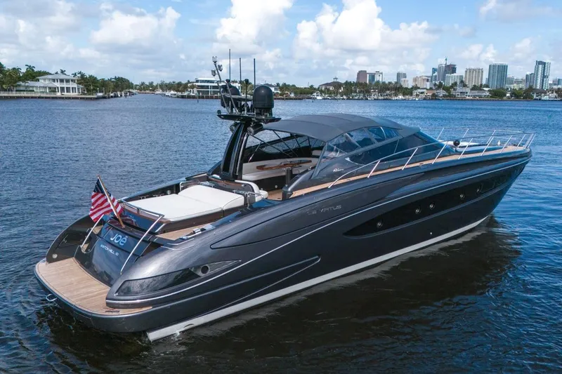 Slide: The Image of Luxurious 2015 Riva 63 yacht cruising on a serene waterway with city skyline backdrop. - 12