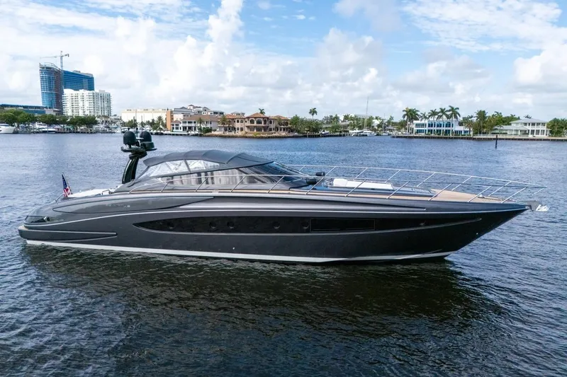 Slide: The Image of Luxurious 2015 Riva 63 yacht cruising on a serene waterfront with cityscape backdrop. - 14