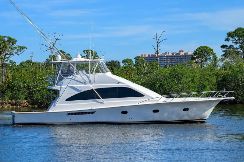 The Image of 2006 Ocean Yachts 57 Super Sport cruising on a serene waterway, surrounded by lush greenery. - 0