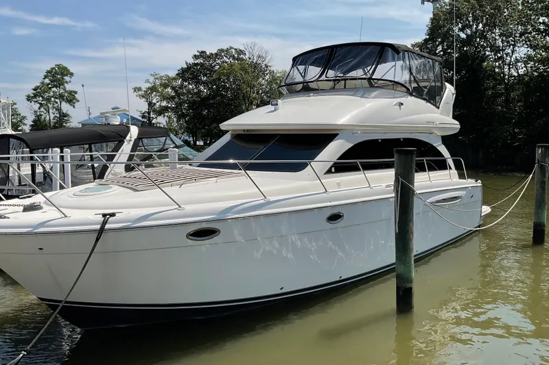 Slide: The Image of 2005 Azimut Fly 50 yacht docked in a marina, surrounded by calm water and trees. - 3