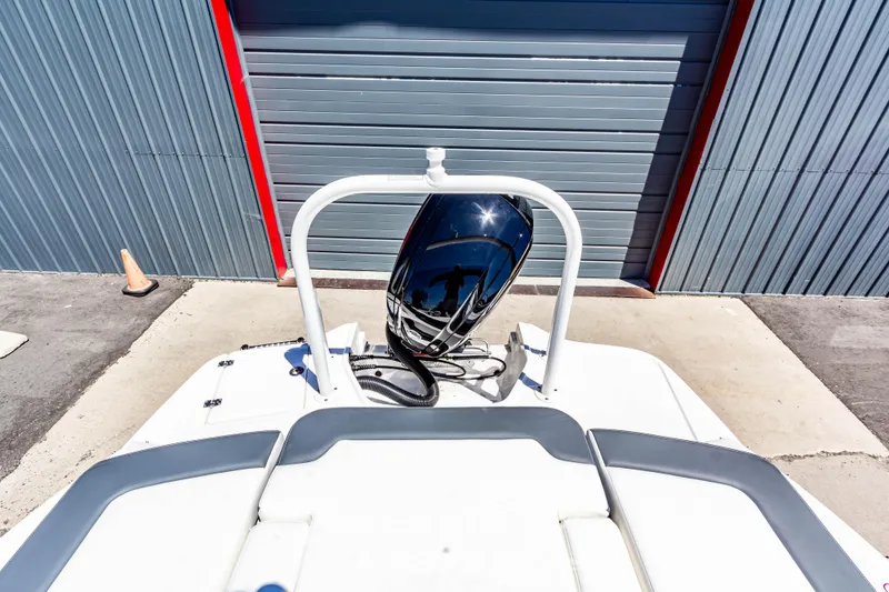 Slide: The Image of 2024 Chaparral 19 SSi OB boat with outboard motor, docked near a metal garage. - 10