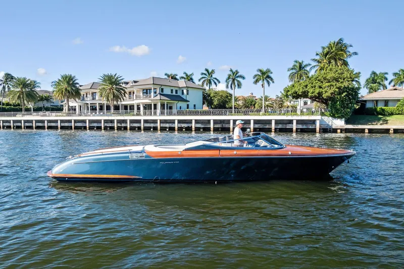 The Image of 2013 Riva 33 Aquariva boat cruising on a sunny day near waterfront homes. - 1
