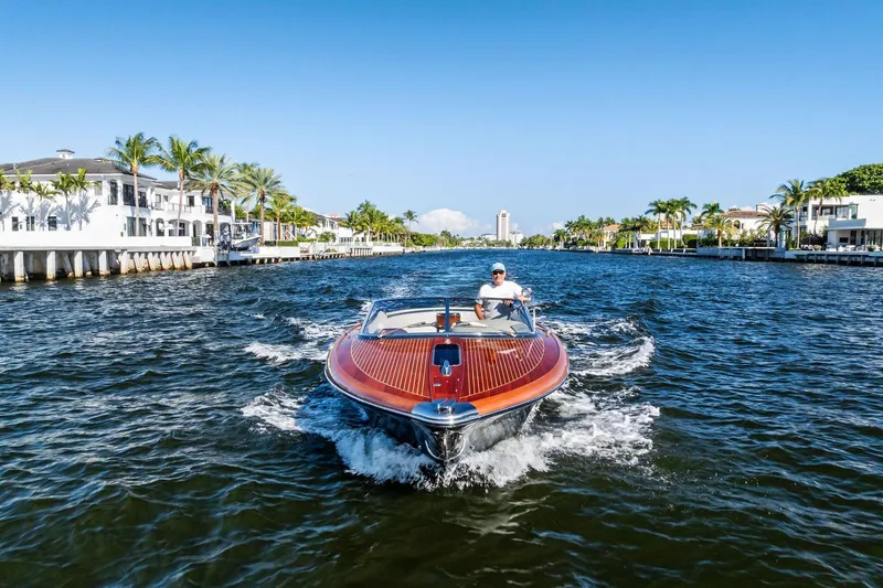 Slide: The Image of 2013 Riva 33 Aquariva cruising on a sunny waterfront, surrounded by palm trees and luxury homes. - 26