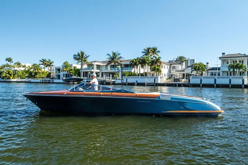 Slide: The Image of 2013 Riva 33 Aquariva boat cruising on a sunny waterfront with luxury homes. - 4