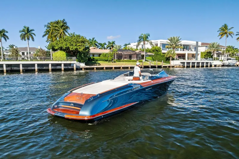 Slide: The Image of 2013 Riva 33 Aquariva luxury boat cruising near waterfront homes and palm trees. - 2