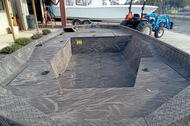 Slide: The Image of 2026 Alweld 1552 Invader boat with textured interior, parked near a tractor. - 13