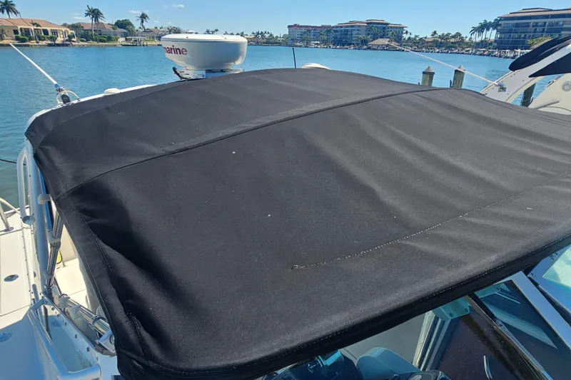 Slide: The Image of 2001 Tiara Yachts 3100 Open with black canvas top, docked by waterfront homes. - 12