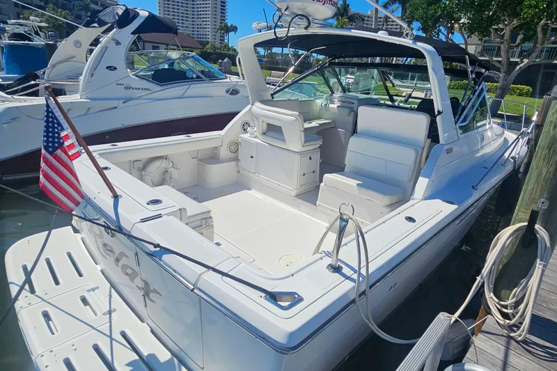 Slide: The Image of 2001 Tiara Yachts 3100 Open docked, featuring spacious seating and American flag. - 18