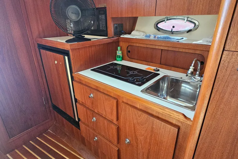 Slide: The Image of 2001 Tiara Yachts 3100 Open galley with stove, sink, and wooden cabinetry. - 23