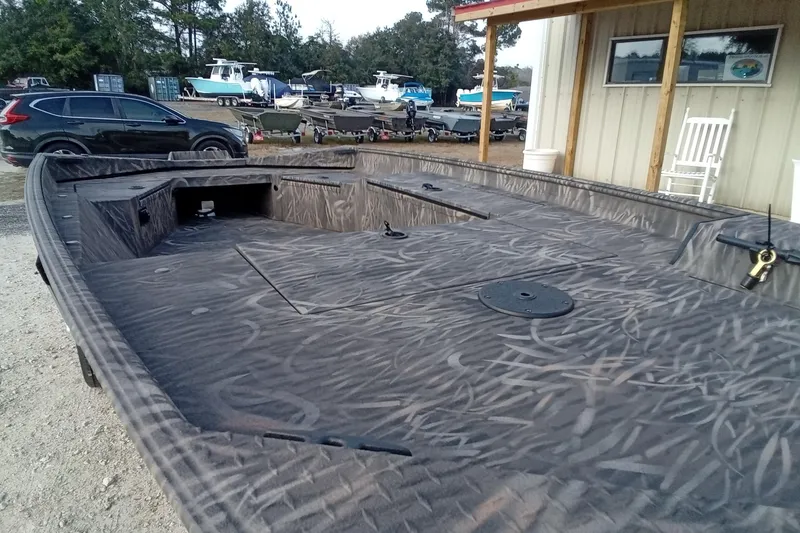 Slide: The Image of 2026 Alweld 1652 Invader boat with camouflage design, parked outdoors near other boats. - 6