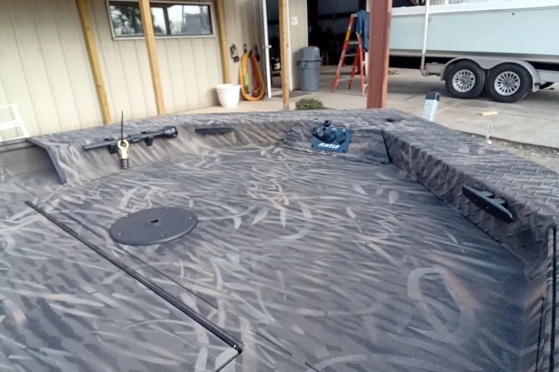 Slide: The Image of 2026 Alweld 1652 Invader boat with camo pattern, parked in a garage. - 7