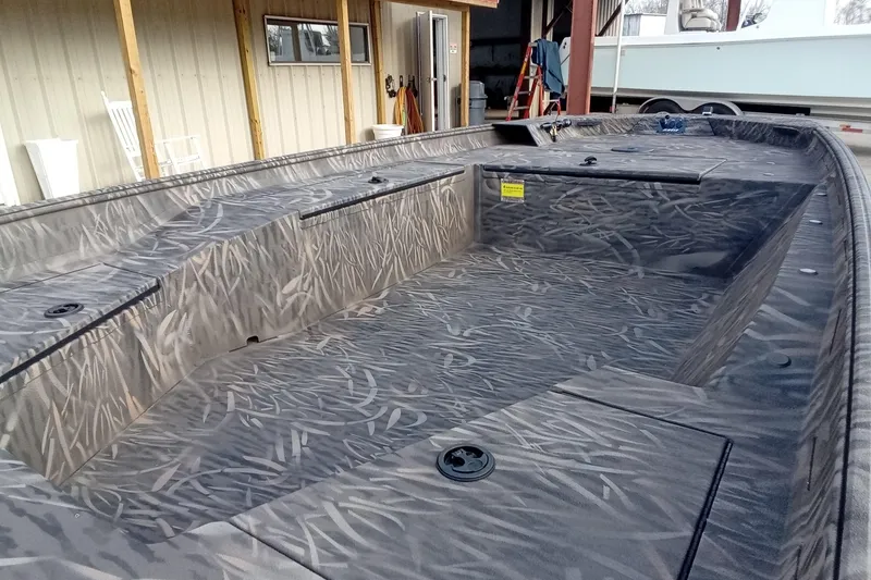 Slide: The Image of 2026 Alweld 1652 Invader boat with camo interior, docked in a shed. - 9