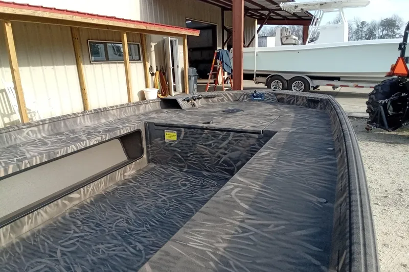 Slide: The Image of 2026 Alweld 1756 Invader boat with camo interior, parked near a building. - 10