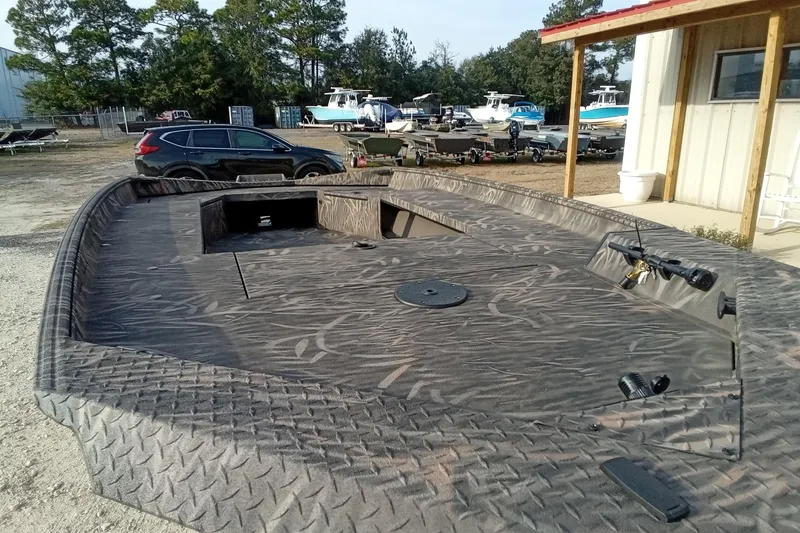 Slide: The Image of 2026 Alweld 1756 Invader boat with camouflage design, parked outdoors near other boats. - 6