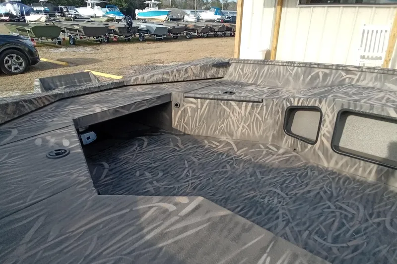 Slide: The Image of 2026 Alweld 1756 Invader boat interior with camo pattern, parked among other boats. - 9