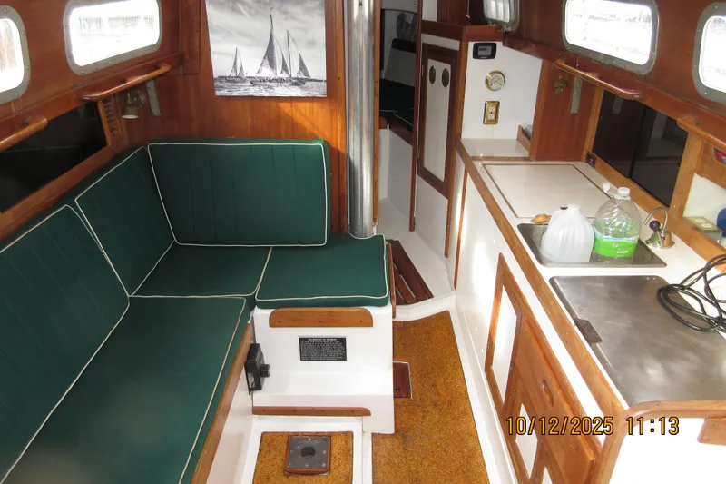 Slide: The Image of 1974 Tartan 30 sailboat interior with green seating, kitchenette, and nautical decor. - 4