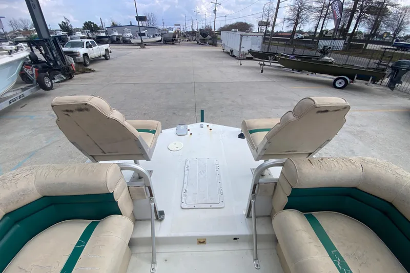 Slide: The Image of 1994 Hurricane FunDeck 226 boat with worn seating, parked in a marina lot. - 12