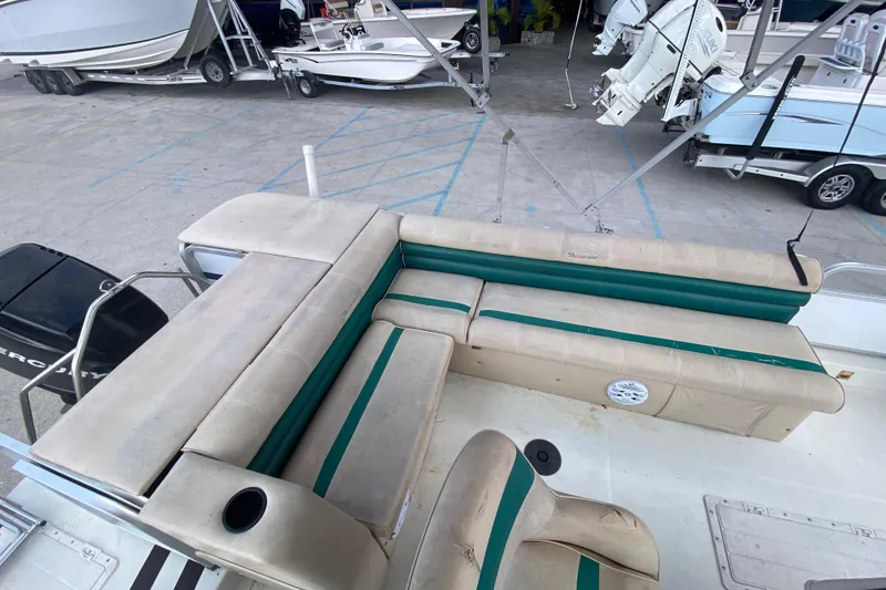 Slide: The Image of 1994 Hurricane FunDeck 226 boat interior with beige and green seating, docked near other boats. - 22