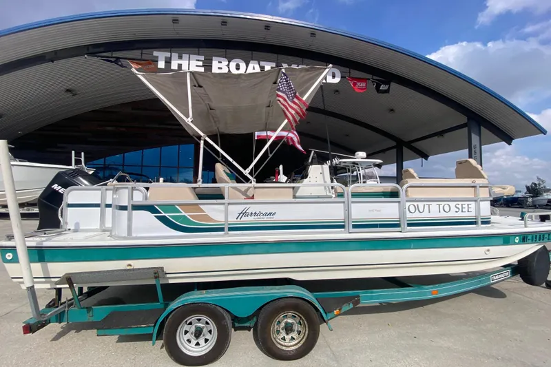 Slide: The Image of 1994 Hurricane FunDeck 226 boat on trailer at The Boat Yard, featuring American flag. - 3