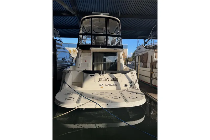 Slide: The Image of 2003 Sea Ray 480 Sedan Bridge docked, rear view, featuring spacious deck and covered upper helm. - 1