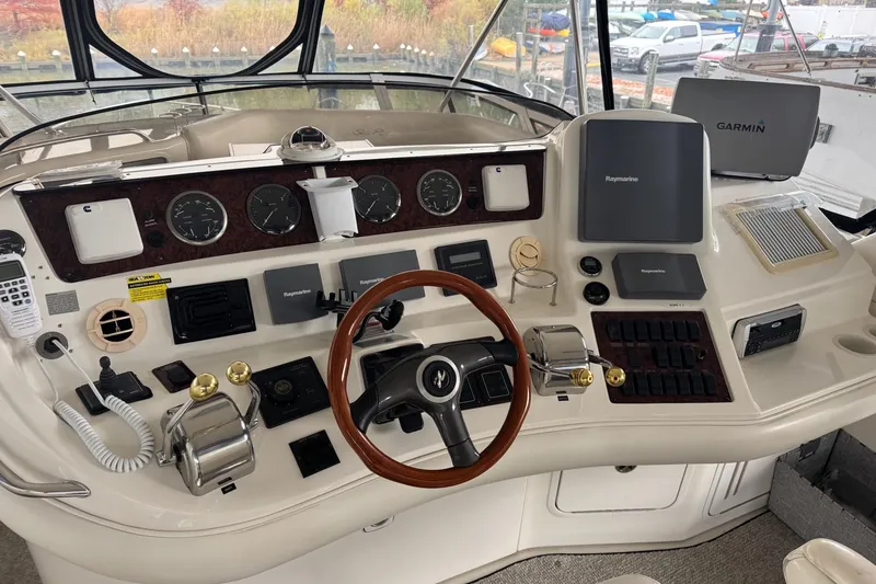 Slide: The Image of 2003 Sea Ray 480 Sedan Bridge helm with navigation equipment and wooden steering wheel. - 28