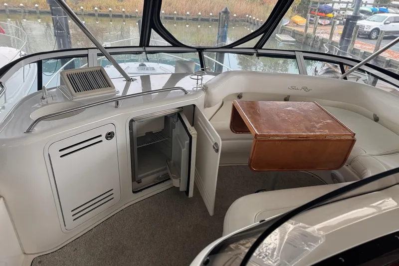 Slide: The Image of 2003 Sea Ray 480 Sedan Bridge interior with seating, table, and open mini-fridge. - 38