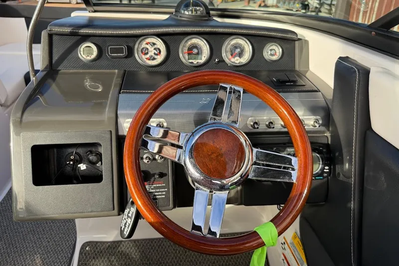 Slide: The Image of 2014 Four Winns SL242 boat dashboard with wooden steering wheel and gauges. - 11