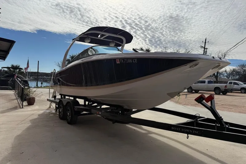 Slide: The Image of 2014 Four Winns SL242 boat on trailer, parked outdoors under cloudy sky. - 2