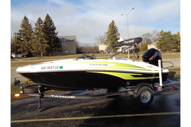 Slide: The Image of 2023 Tahoe T16 boat on trailer, parked outdoors with trees in the background. - 1