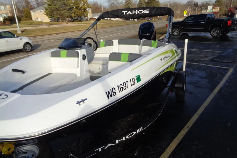 Slide: The Image of 2023 Tahoe T16 boat with green accents parked on a street. - 3
