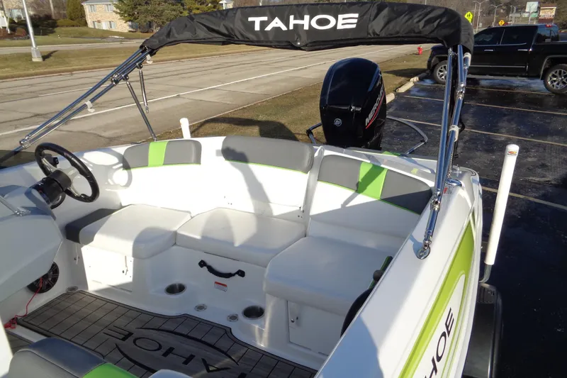 Slide: The Image of 2023 Tahoe T16 boat interior with seating and steering wheel, parked outdoors. - 7