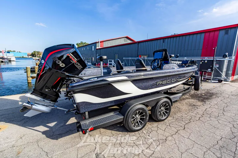 Slide: The Image of 2024 Recon 985 SC boat with powerful outboard motor on trailer near waterfront. - 3