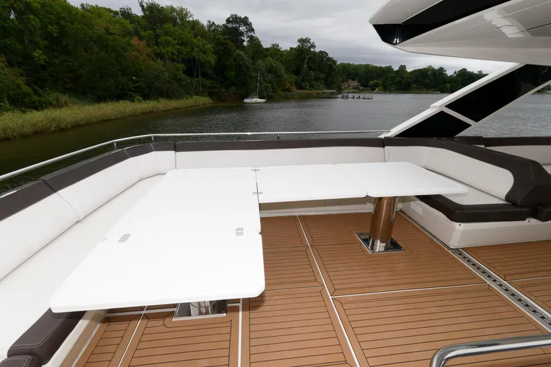 Slide: The Image of Galeon 640 Fly 2018 yacht deck with seating and table, near water and greenery. - 23