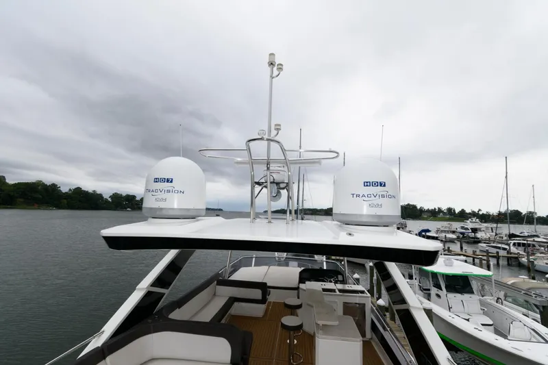 Slide: The Image of 2018 Galeon 640 Fly yacht interior with helm and seating area, docked by a serene waterfront. - 28