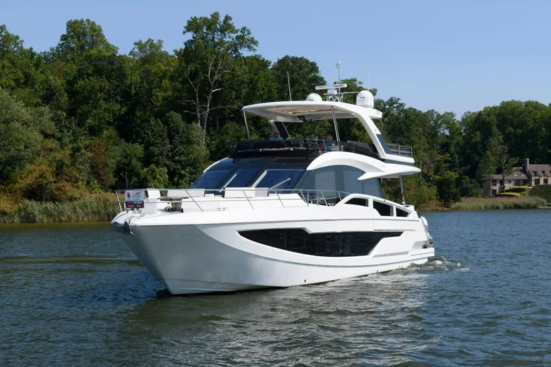 Slide: The Image of 2018 Galeon 640 Fly yacht cruising on a serene lake with lush green trees. - 6