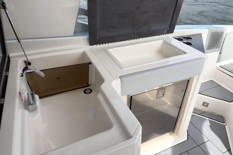 Slide: The Image of 2022 Aviara AV32 OB boat kitchen area with sink, storage, and stainless steel fridge. - 25
