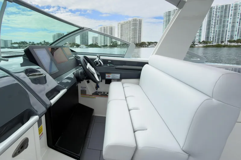 Slide: The Image of 2022 Aviara AV32 OB boat interior with modern helm and white seating, cityscape in background. - 32