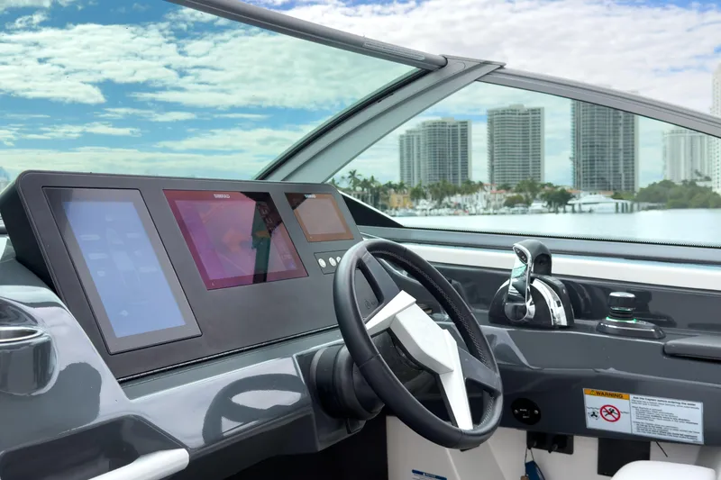 Slide: The Image of 2022 Aviara AV32 OB boat dashboard with modern controls and city skyline view. - 33