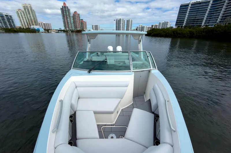 Slide: The Image of 2022 Aviara AV32 OB boat with sleek design on a calm waterway, city skyline backdrop. - 40