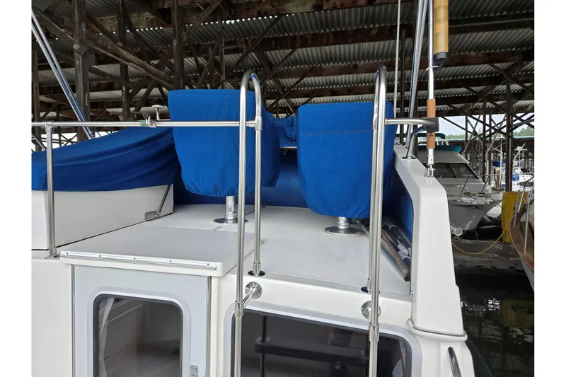 Slide: The Image of 2001 Commander Flybridge Sedan with blue covers, docked under a metal roof. - 12