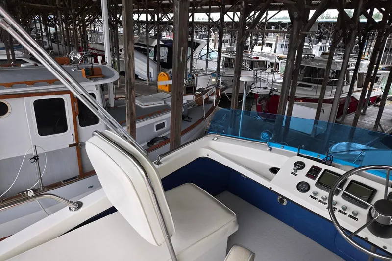 Slide: The Image of 2001 Commander Flybridge Sedan in marina, showcasing helm and docked boats. - 23