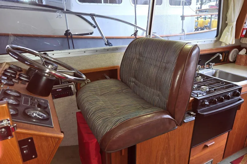 Slide: The Image of 2001 Commander Flybridge Sedan interior with steering wheel, cushioned seat, and kitchen area. - 54