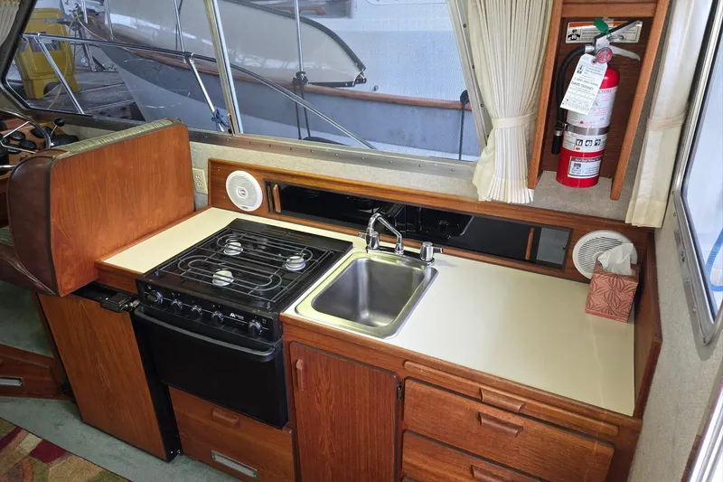Slide: The Image of 2001 Commander Flybridge Sedan kitchen with stove, sink, and fire extinguisher. - 70