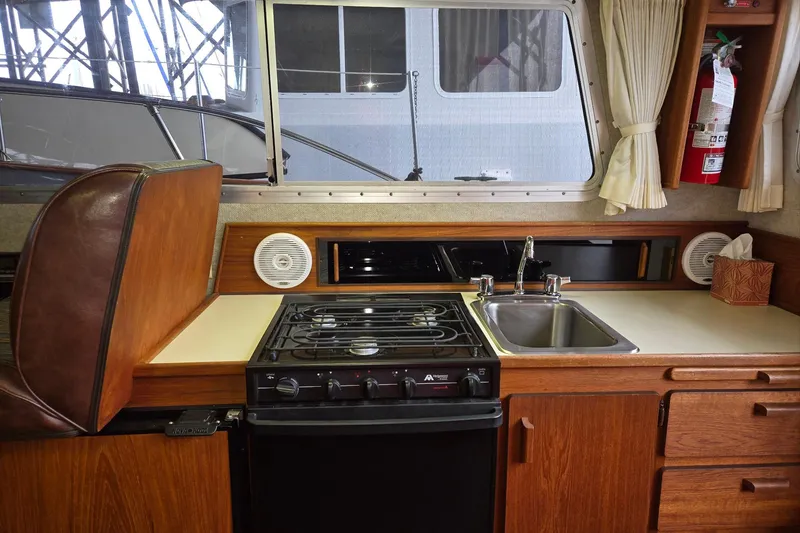 Slide: The Image of 2001 Commander Flybridge Sedan kitchen with stove, sink, and wooden cabinetry. - 71