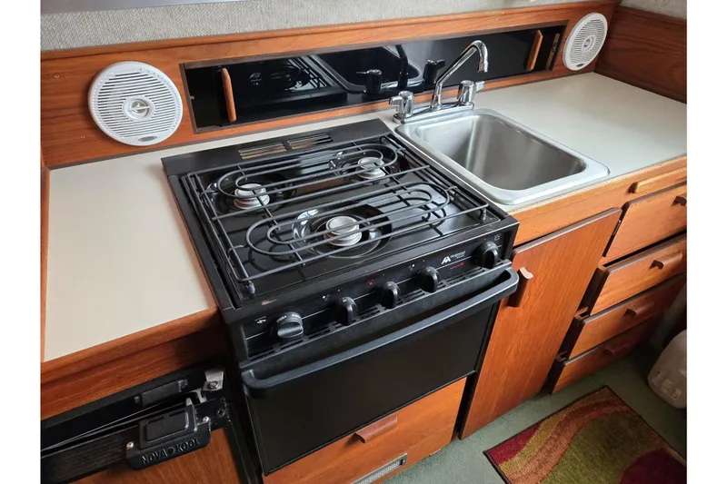 Slide: The Image of 2001 Commander Flybridge Sedan kitchen with stove, sink, and wooden cabinetry. - 73