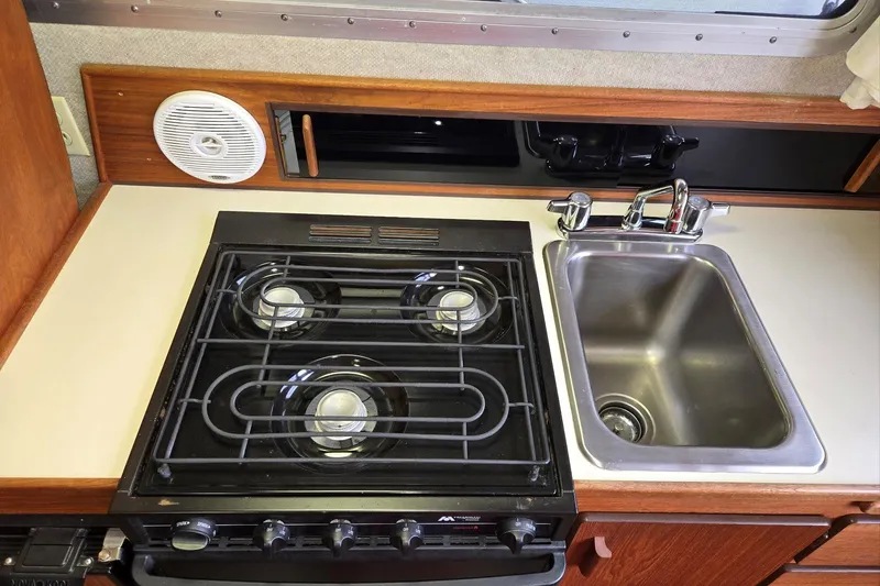 Slide: The Image of 2001 Commander Flybridge Sedan kitchen with stove, sink, and wooden cabinetry. - 74