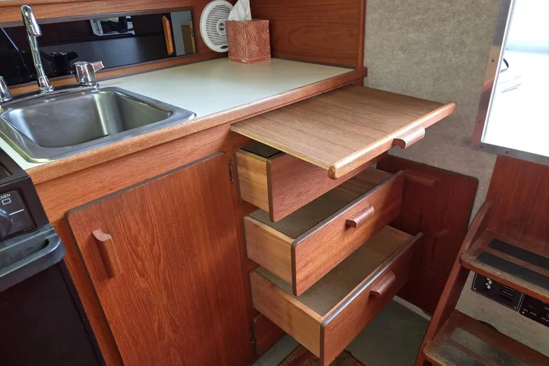 Slide: The Image of 2001 Commander Flybridge Sedan kitchen with wooden cabinets, drawers, and stainless steel sink. - 78