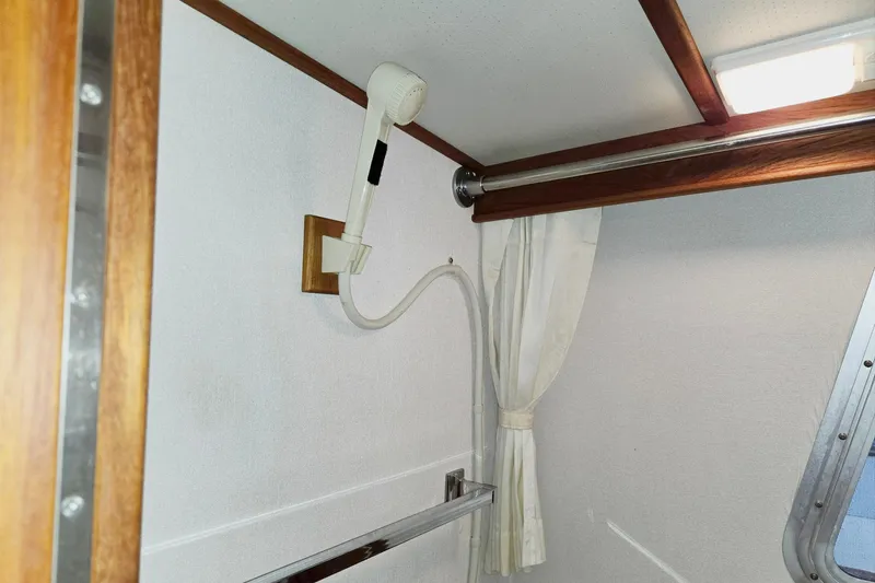 Slide: The Image of 2001 Commander Flybridge Sedan interior shower area with white walls and wooden accents. - 95