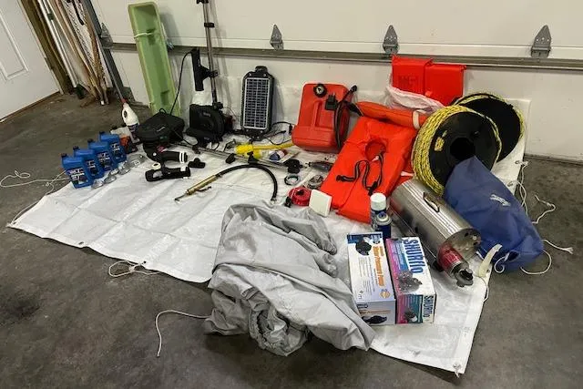 Slide: The Image of Boat equipment and supplies for a 2001 Commander Flybridge Sedan, organized on a garage floor. - 96